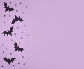 Halloween Background with Black Flying Bats. Little Bats and Stars on a Violet Background. Halloween Flat Lay. Top View Composition ideal for Card, Banner, Flyer.