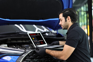 Car mechanic working with a notebook in Auto Repair Service checking car engine.