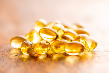 Fish oil capsules. Yellow omega 3 pills on wooden table.