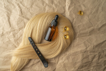 A hair treatment essential oil for smoothing hair and a hair curling styler lying on a brown craft...
