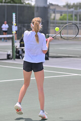 Young girl hitting the tennis ball during a competitive tennis match