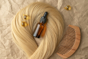 Fototapeta premium A hair treatment essential oil for smoothing hair lying on a strand of blond hair