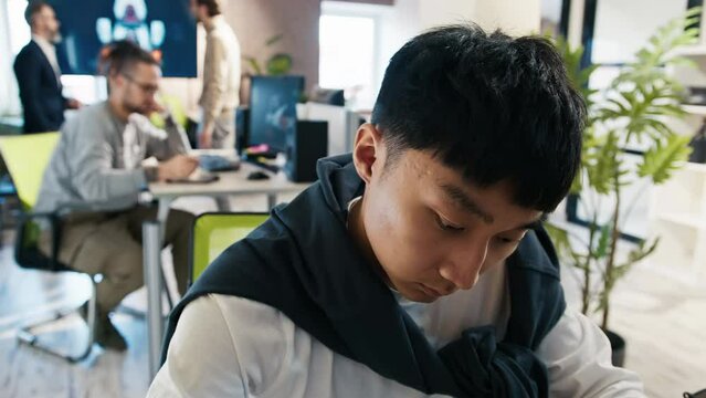 An Asian and European man looks at the camera as if in a monitor in an office for the development of games and computer applications.