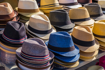 Fedora style hats in various colors stacked on a table ready for sale.