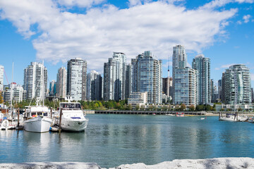 Fototapeta na wymiar Boats sit idle in a marina on False Creek with the Vancouver's Yaletown neighborhood skyline in the background.
