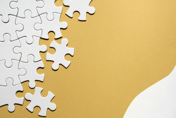 Jigsaw puzzle pieces half assembled and separate. Top view, flat lay on monochromatic abstract...