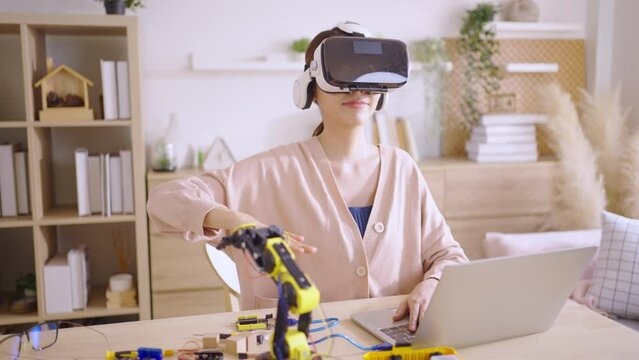 Young Asian woman engineer programer wear vr control learning robot arm ai coding programer working on robotics project  at home
