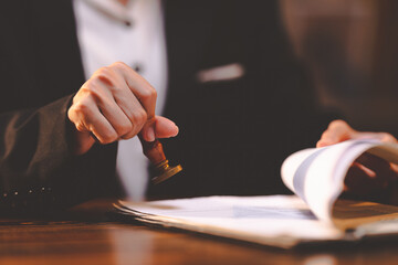 businesswoman person's hand stamping with approved stamp on certificate document public paper at desk, people work in notary law or business finance agreements, lawyer paperwork in confidential