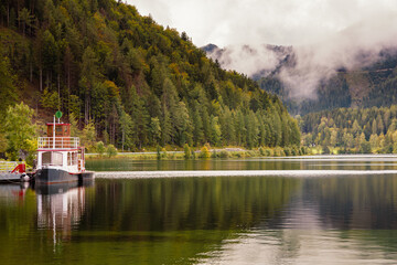 Fototapeta premium Erlaufsee mit einem Boot Wald und grünem Wasser Wolken nach dem Regen