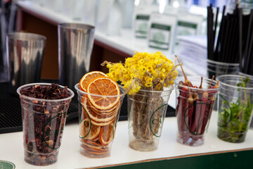 Dried orange, mint, chamomile, rose and red pepper in plastic container. Fruit cocktail. Bartender drink decorations. Alcohol cocktail.