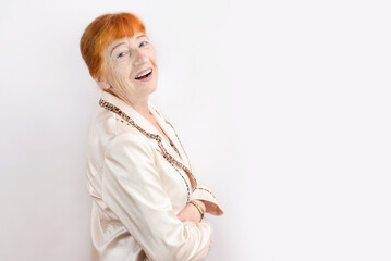 A beautiful senior woman with red hair and freckles on her face and hands sincerely smiles, laughs...