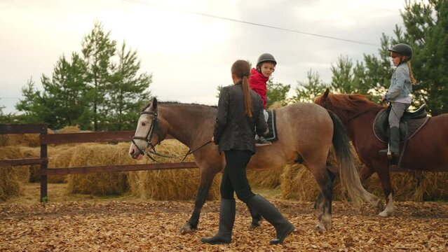 hippotherapy for children in pony club, little boy is sitting on horseback and riding, coach is helping