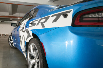 Installation of black foil decals on a blue luxury fast car in the garage.