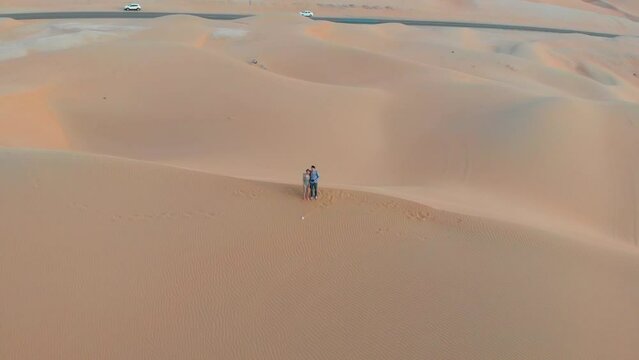 Couple enjoying romantic scenic sunset in a desert aerial view. Drone selfie of a couple in the Liwa desert in Abu Dhabi Emirate in the United Arab Emirates