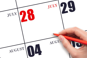 A hand holding a red pen and pointing on the calendar date July 28. Red calendar date, copy space,...