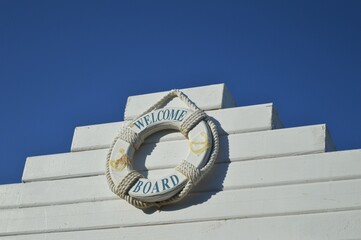 An old lifebuoy surrounded by a sailor's rope and a welcome board sign