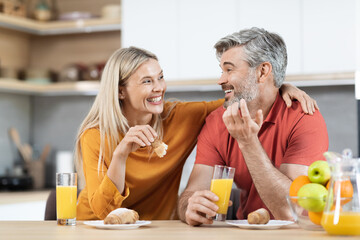 Cheerful man and woman having snack and talking at home
