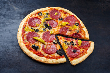 Traditionelle italienische Pizza al salame mit Salami, Mozzarella und Oliven serviert als close-up auf einem alten rustikalen Board mit Textfreiraum 