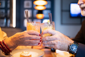 Two older people celebrating and toasting at the bar