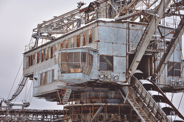 abandoned giant bucket wheel excavator stands in a field in winter