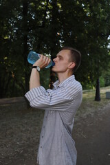 Young man drinking water from bottle becouse he's thirsty
