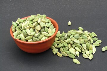 Green cardamom in a bowl on black background 