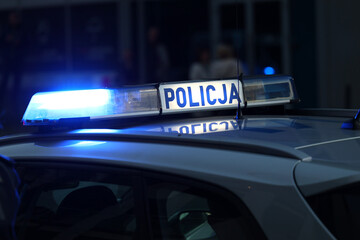 Radiowóz polska policja z  Sygnalizator błyskowy niebieski na dachu radiowozu.  Alarmowo wieczorem. 