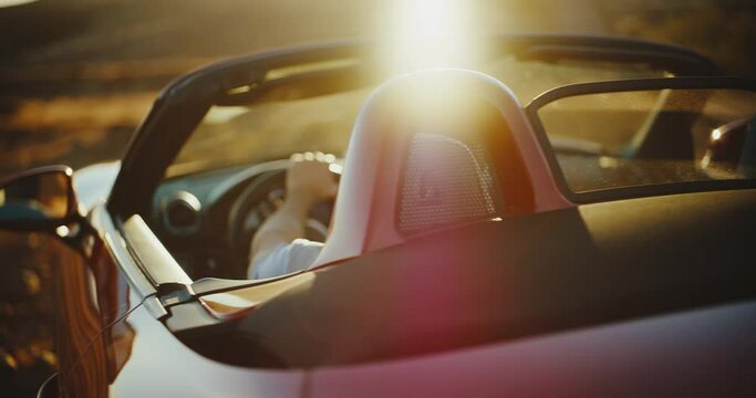 Successful young man in luxury convertible sports car watching the sunset
