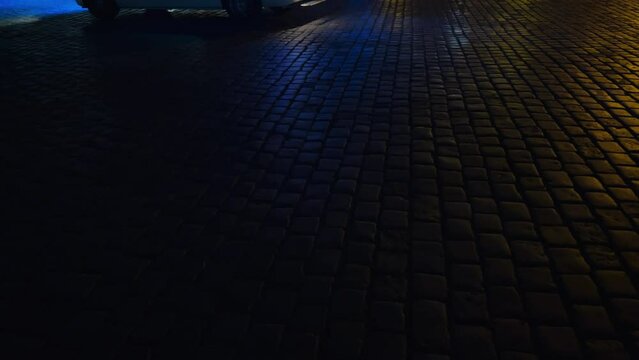 Old city crime scene view over a brickstone pathway against a police car in the background with flashing siren lights