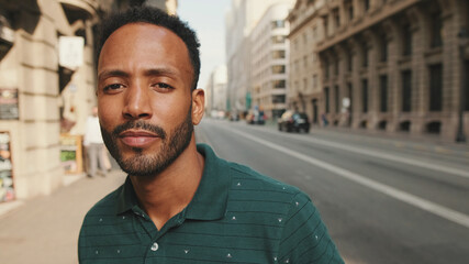 Close-up of happy young man standing on the street. Guy turns his head and smiles at the camera