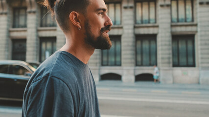 Profile of young smiling man with beard walking down the street