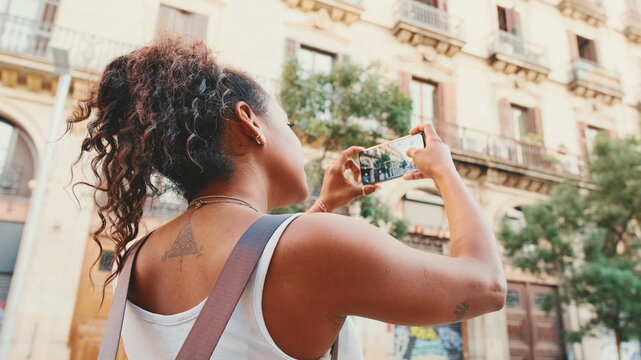Young mixed race woman uses cell phone, takes photo of the old city