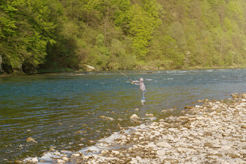 Boy catching fish in a mountain river. Throws the fishing rod.