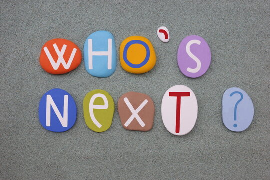 Naklejki Who is next, creative question composed with multi colored stone letters over green sand