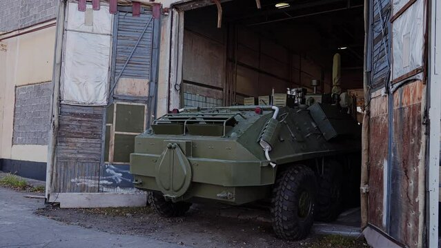 A military armored vehicle leaves the hangar, turning around in an empty place. General plan shooting