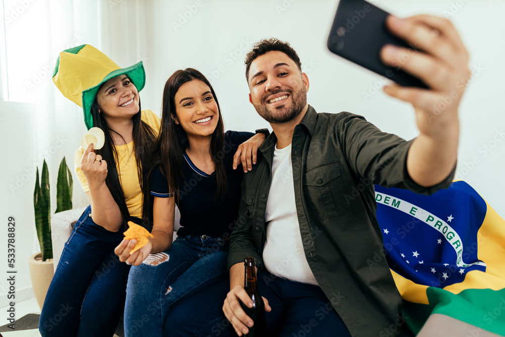 Wall mural Group of Brazilian friends watching a football match on TV