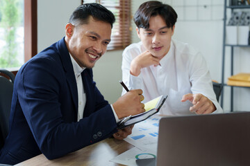 Young economists or accountants or financiers and investors are reviewing budget documents and using computers to study impact and risk assessments on corporate investment management.