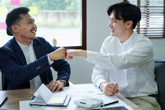 Portrait of two young Asian entrepreneurs congratulating them with smiling faces after successful investment negotiations