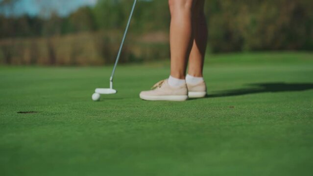 While playing golf, a girl hits the ball with a club and it hits the hole