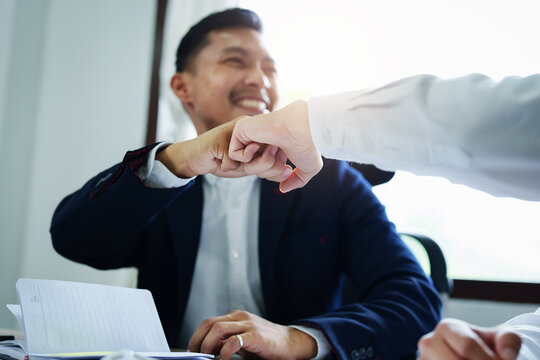 Portrait of two young Asian entrepreneurs congratulating them with smiling faces after successful investment negotiations