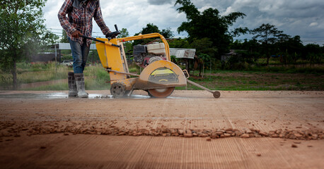 Construction workers operate concrete road cutters at a rural construction site.
