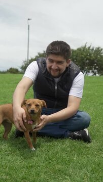 a latin adult man pets his brown pinsher