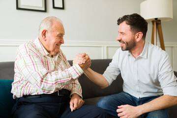 Cheerful senior father and son laughing while shaking hands
