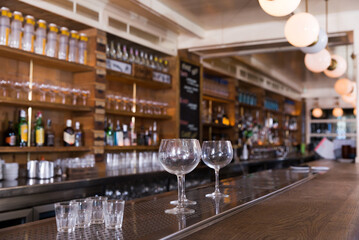 Empty wine glasses at bar counter with blurry restaurant background scene