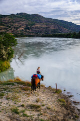 Fototapeta na wymiar Chile, Aysen, Rio Baker. Woman horsepacking along Baker river. (MR)