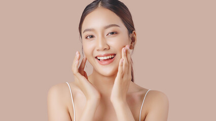 Close up perfect beauty face of young beautiful Asian woman massages her face gently with fingertips isolated on brown background.