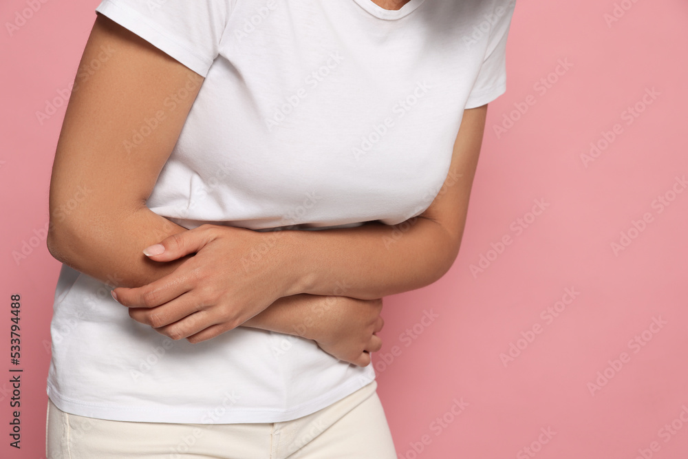 Wall mural Young woman suffering from menstrual pain on pink background, closeup. Space for text