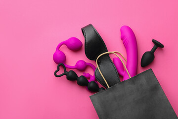 Shopping bag with different sex toys on pink background, flat lay. Space for text - obrazy, fototapety, plakaty