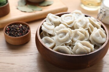Tasty dumplings in bowl on wooden table, closeup