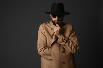 Exhibitionist in coat and hat on black background
